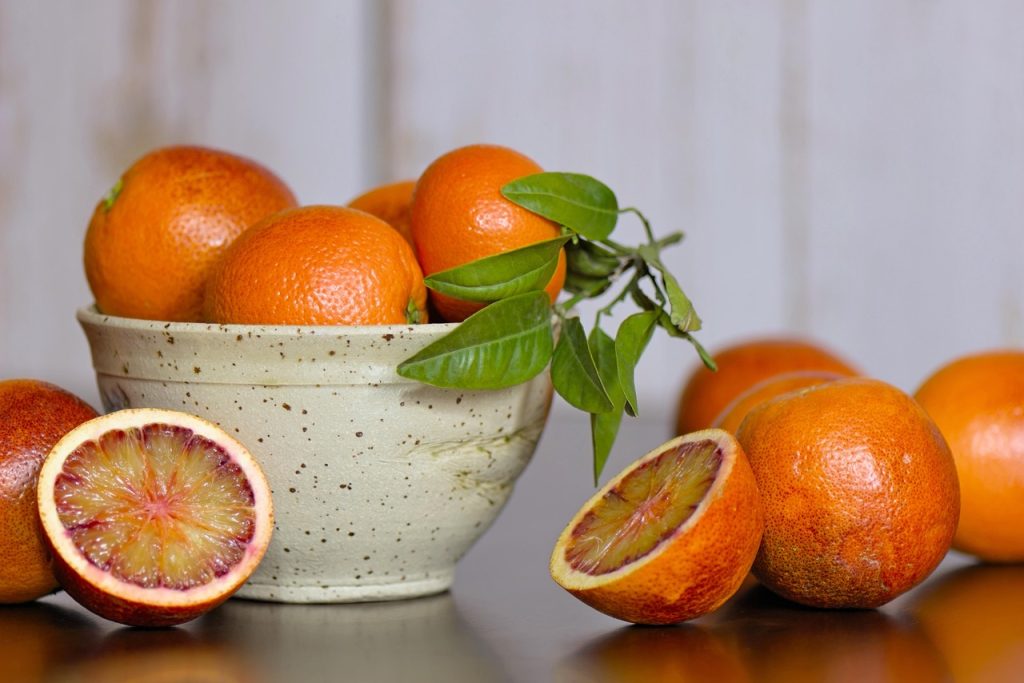 Bright ripe orange with water droplets on a wooden cutting board
